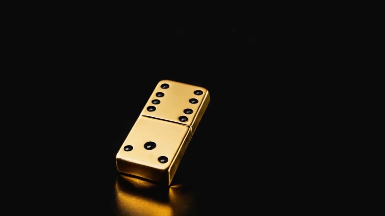 Karanlıkta düşen tek bir domino taşının altın ışıkla parlaması, tarihin küçük tetikleyicilerini simgeliyor